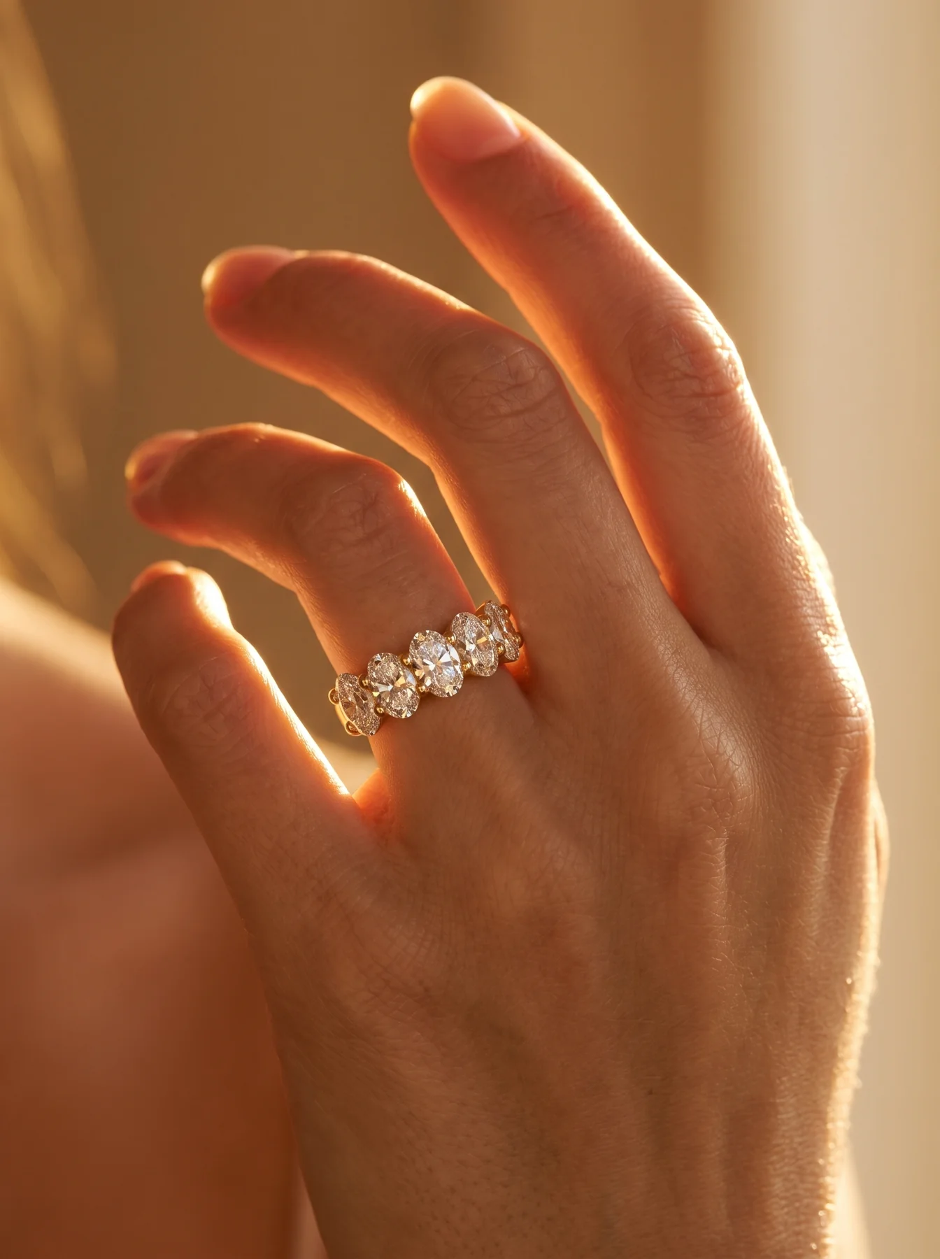 Oval diamond gold ring worn on a hand in warm light